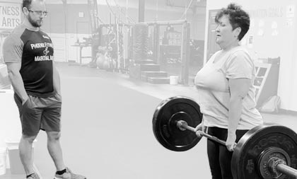 Woman lifting weights while Coach watches