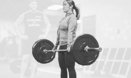 Coach watching as Woman lifts weights